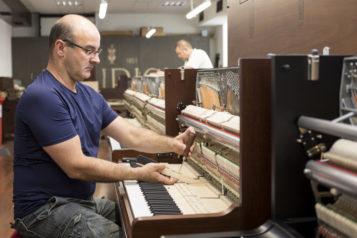Ein Experte hantiert in der Klaviermanufaktur an einem offenen Klavier