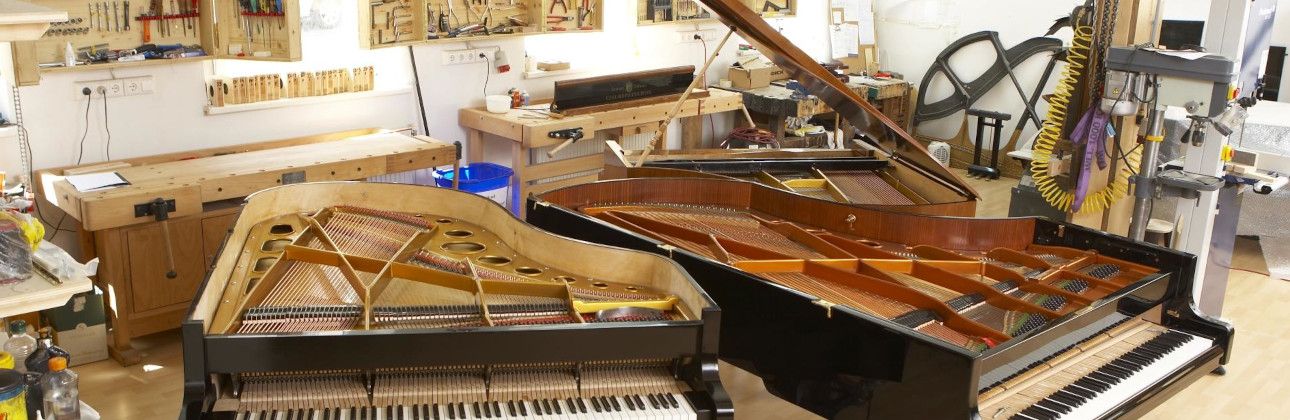 Zwei offene Flügel in der wiener Klavierwerkstatt - im Hintergrund sieht man eine Hobelbank und Regale in denen diverse Werkzeuge liegen